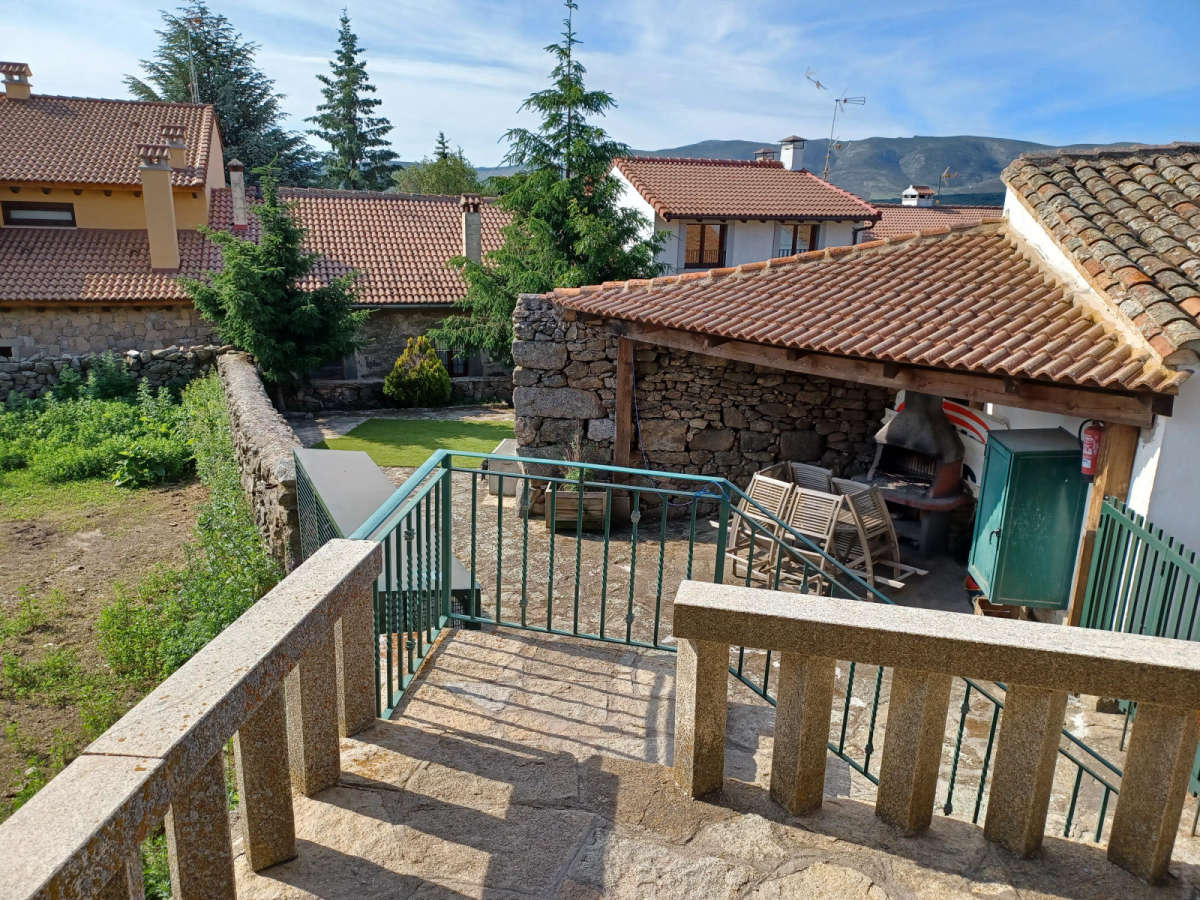 Patio exterior con barbacoa cubierta bajo el porche Casa Rural La Libélula de Gredos